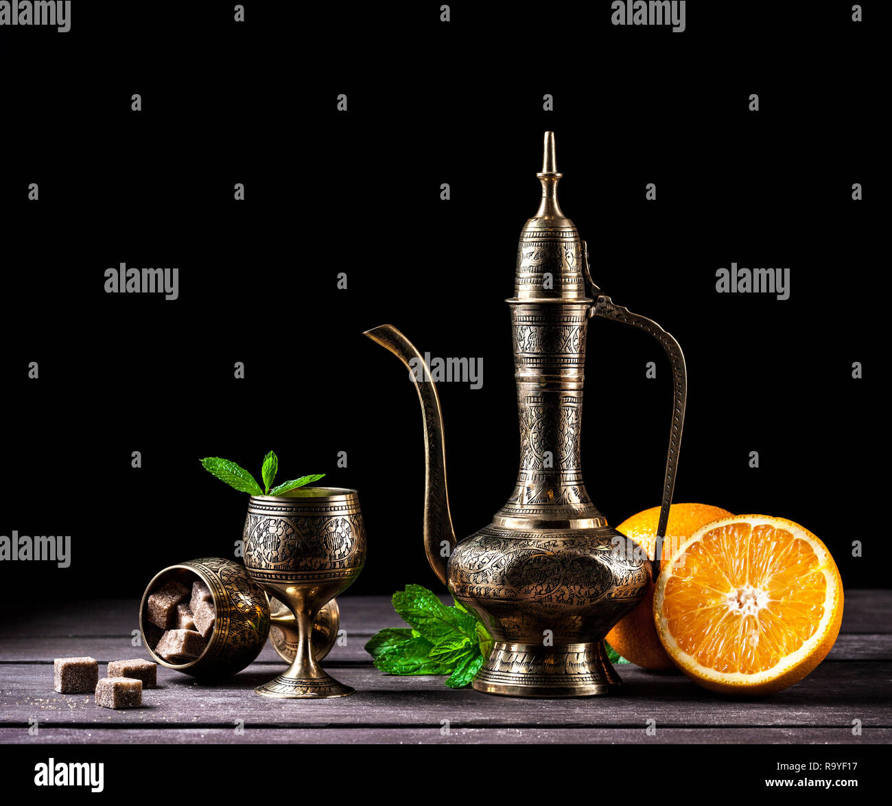 Thé marocain à la menthe et des oranges dans oriental cooper pot et tasses sur fond de bois rustique Banque D'Images