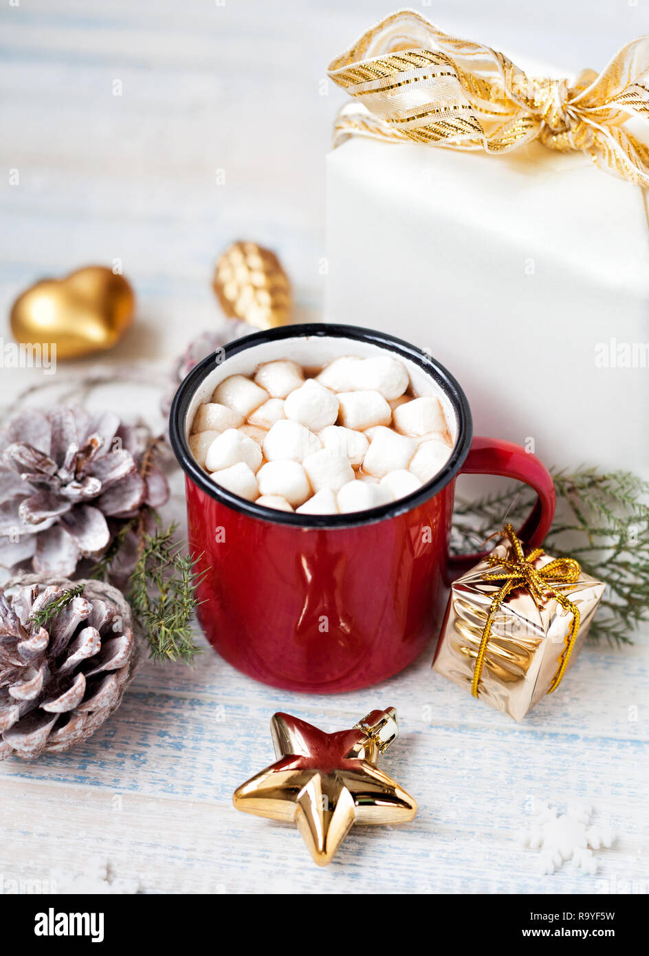 Le cacao avec des guimauves en rouge mug près de l'actuelle et golden jouets sur table en bois en hiver Banque D'Images