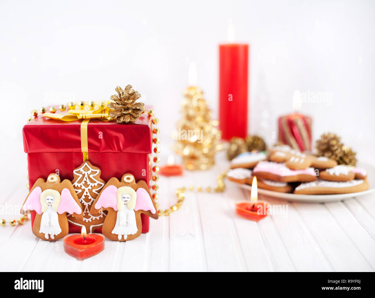 Angels cookies près de red boîte cadeau et bougies sur fond blanc à Noël Banque D'Images