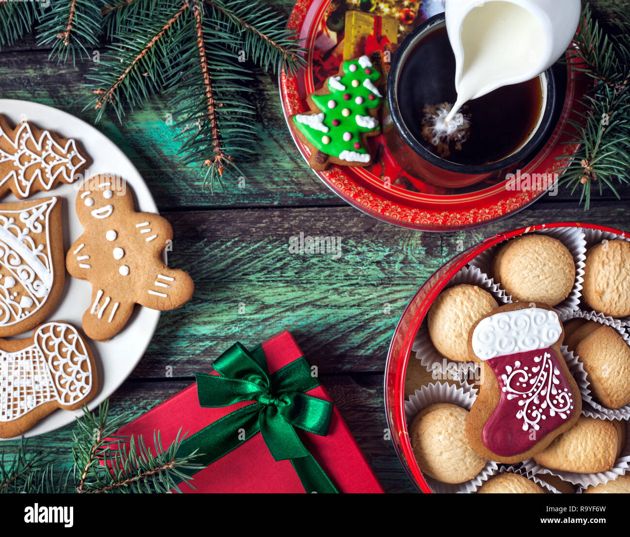 Les biscuits de Noël, rouge présent et tasse de café au lait sur fond vert en bois Banque D'Images