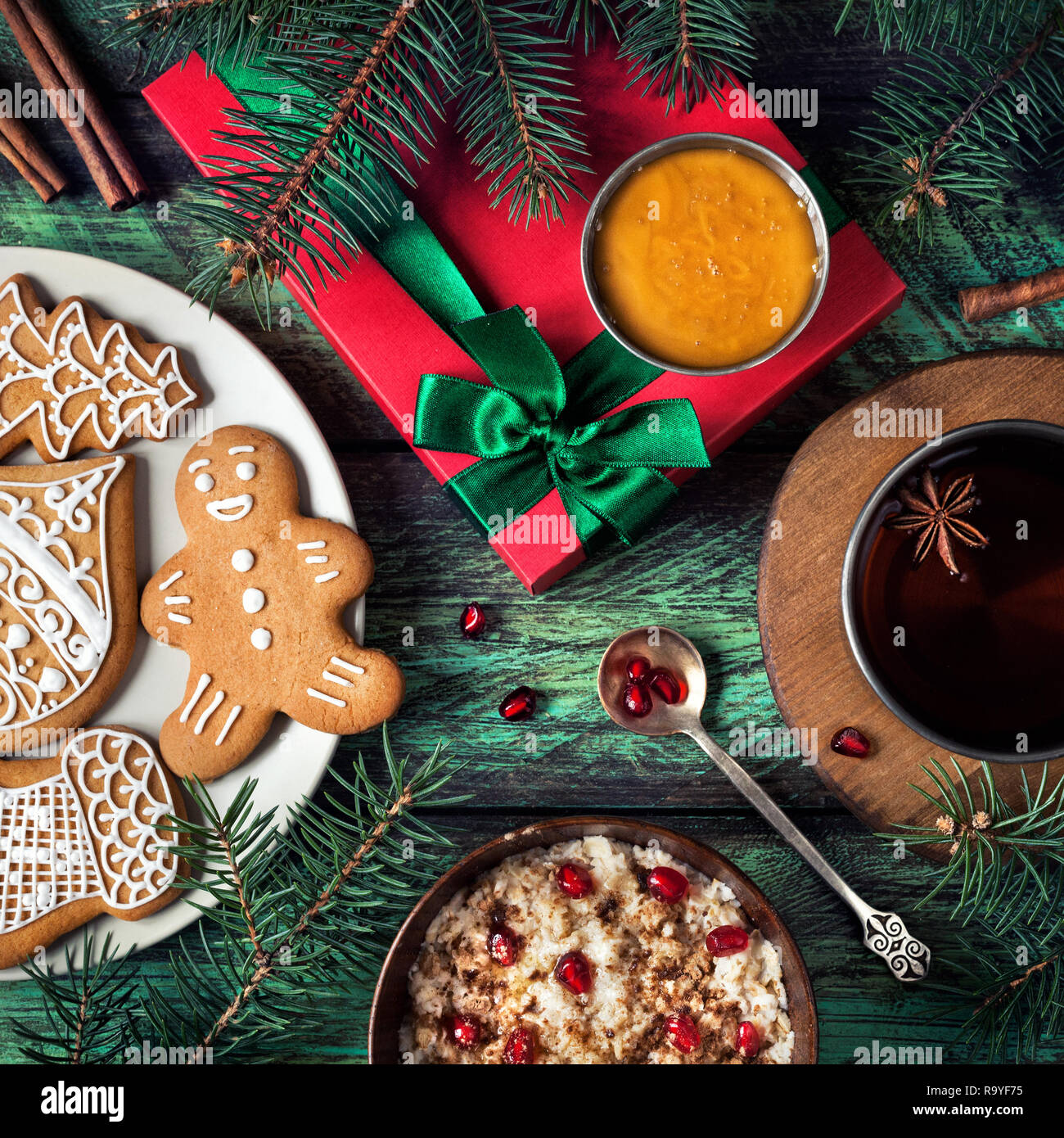 Les biscuits de Noël, du porridge avec du miel et de grenade, le thé avec des épices et du présent sur fond vert en bois Banque D'Images
