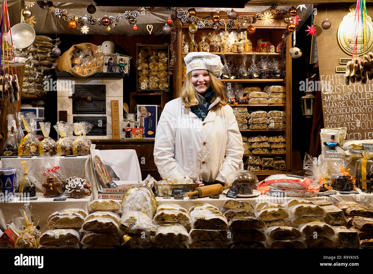 Une vendeuse de vente habituel Noël nourriture comme le traditionnel pain aux fruits (stollen) derrière son étal au marché de Noël à Leipzig, Allemagne. Banque D'Images