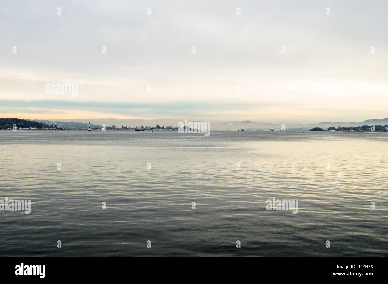 Oslofjord fines côtes avec deux bateaux traversiers locaux et deux phares blancs en hiver calme au coucher du soleil. Banque D'Images