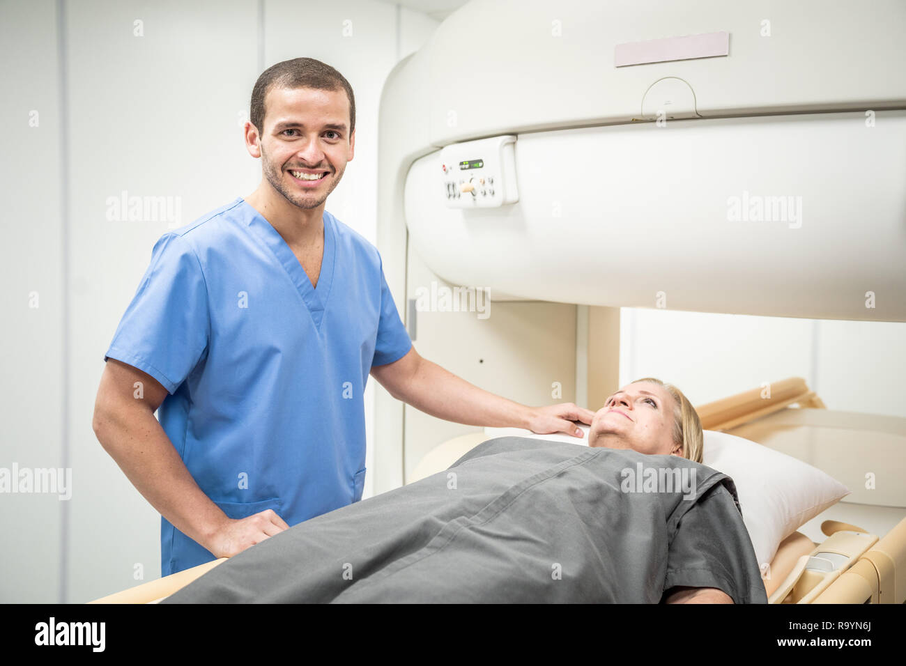 Technicien de laboratoire mâle femme seniro aider après l'IRM en laboratoire hospitalier. Young caucasian doctor examining vieille femme pour examen médical en clinique. Peop Banque D'Images