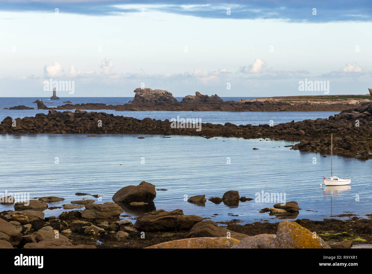 Porspoder, France. Paysage rocheux dans la côte de Bretagne (Bretagne) à l'aube d'une belle journée d'été, avec un bateau et un phare Banque D'Images
