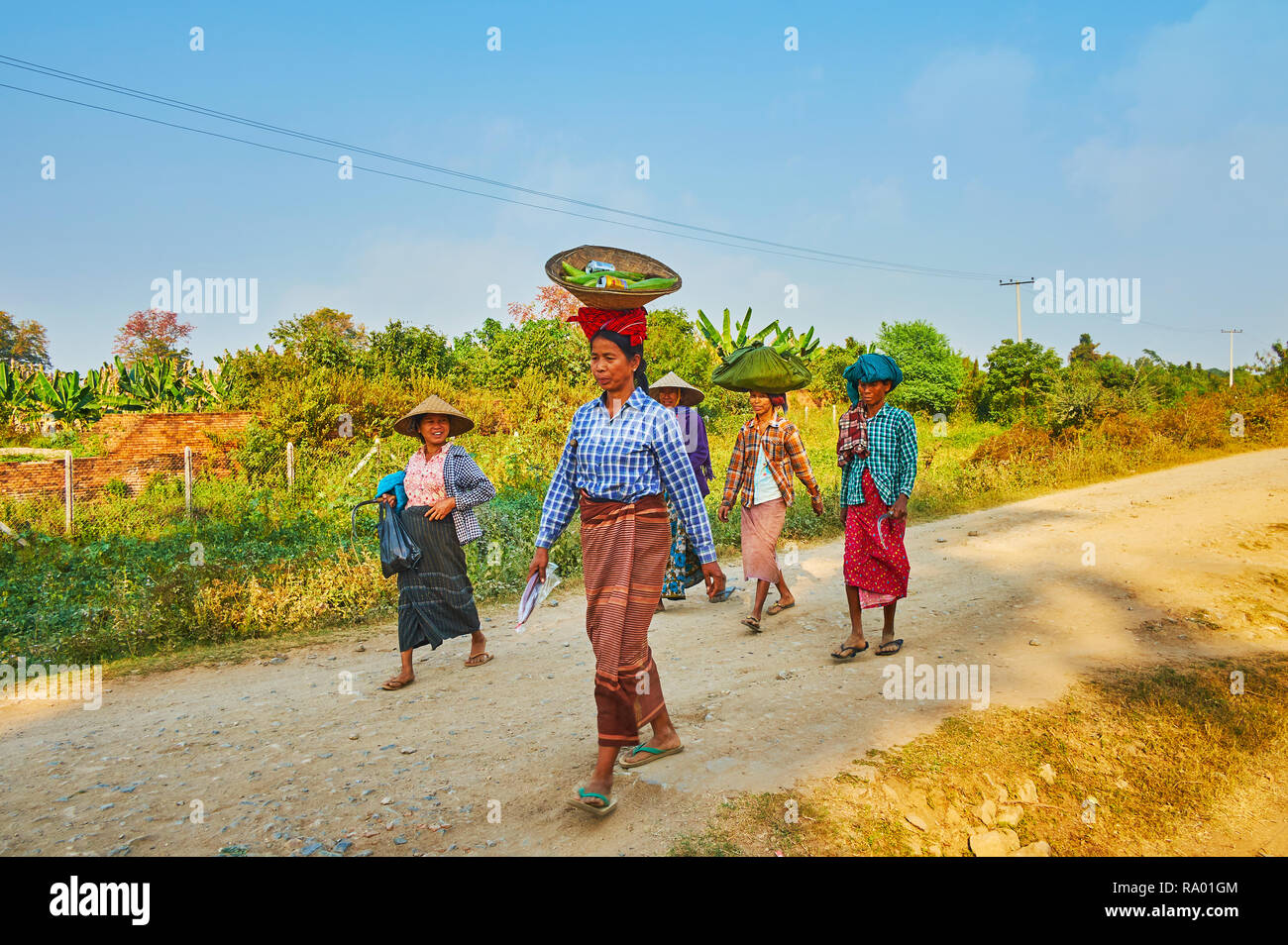 AVA, LE MYANMAR - février 21, 2018 : Le groupe des femmes de paysans birmans remonte après le travail de terrain avec des sacs de nourriture sur la tête, le 21 février à Ava. Banque D'Images