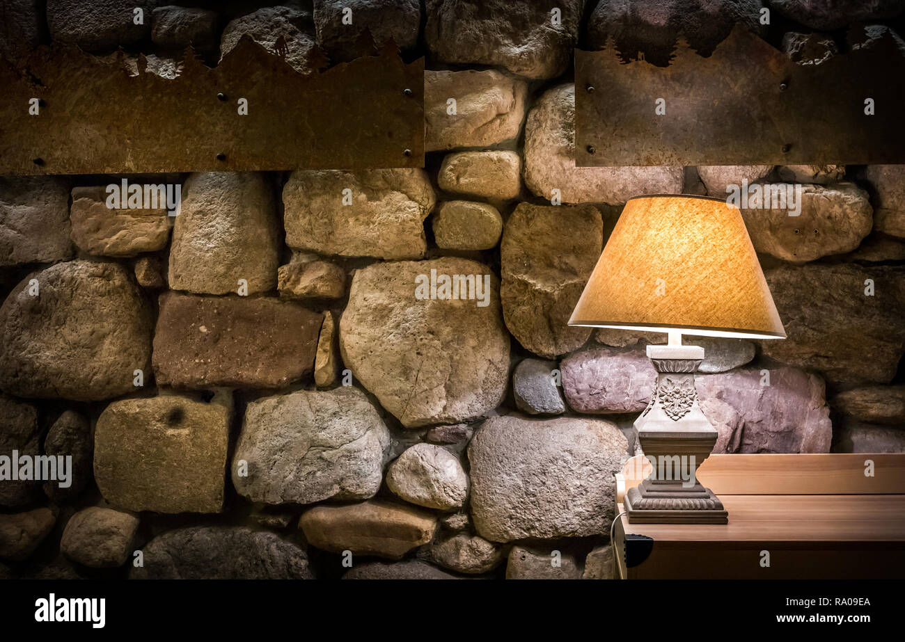 Mur de pierre éclairés par la lampe sur table en bois élégant Banque D'Images