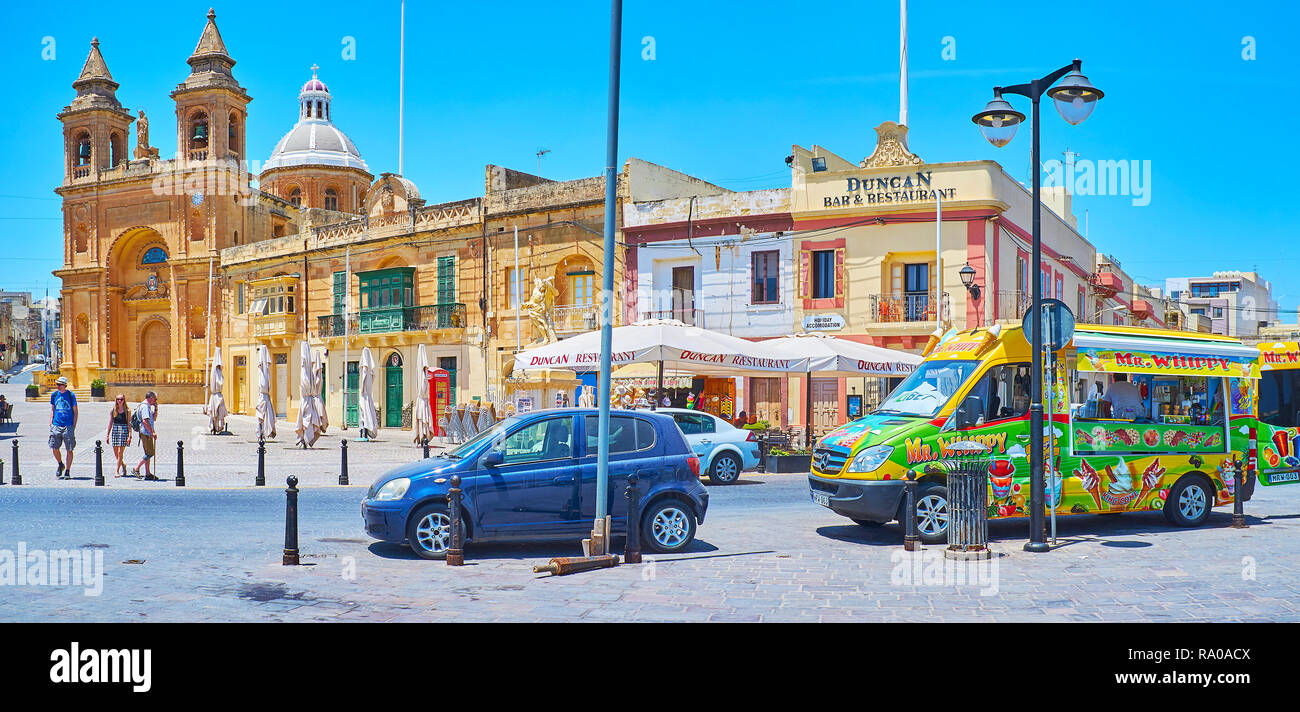 MARSAXLOKK, MALTE - le 18 juin 2018 : la place centrale du village avec l'église Notre Dame de l'Pomei touristiques, cafés et glaces voiture, attirer tou Banque D'Images