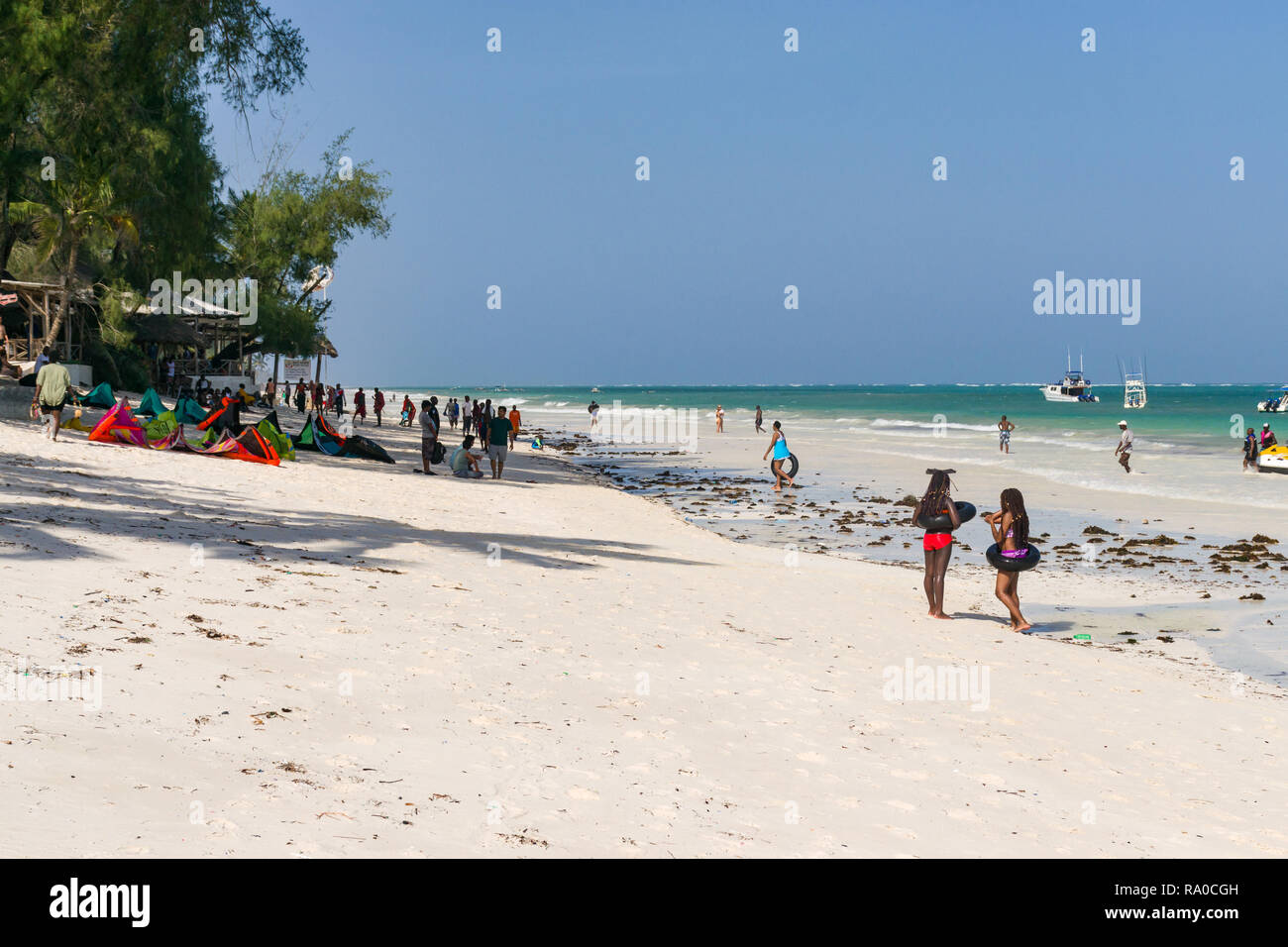 Les touristes et kitesurfers tropical sur la plage de sable blanc de Diani à marée basse sur une journée ensoleillée, au Kenya Banque D'Images