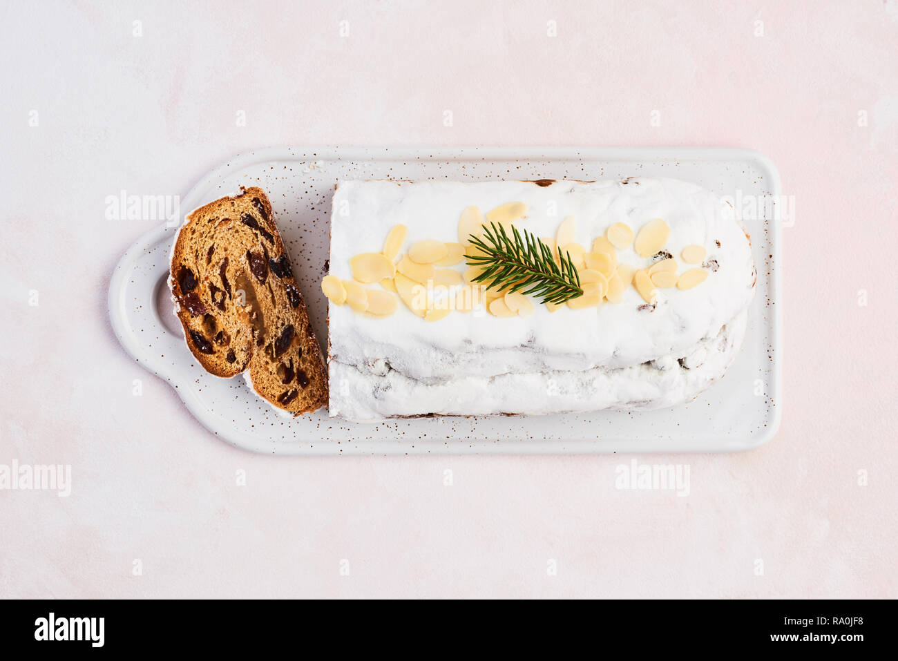 Stollen de Noël gâteau de sucre glace, amandes, amandes et raisins secs sur une assiette blanche sur fond rose. Dresdner traditionnelle pâtisserie christ Banque D'Images
