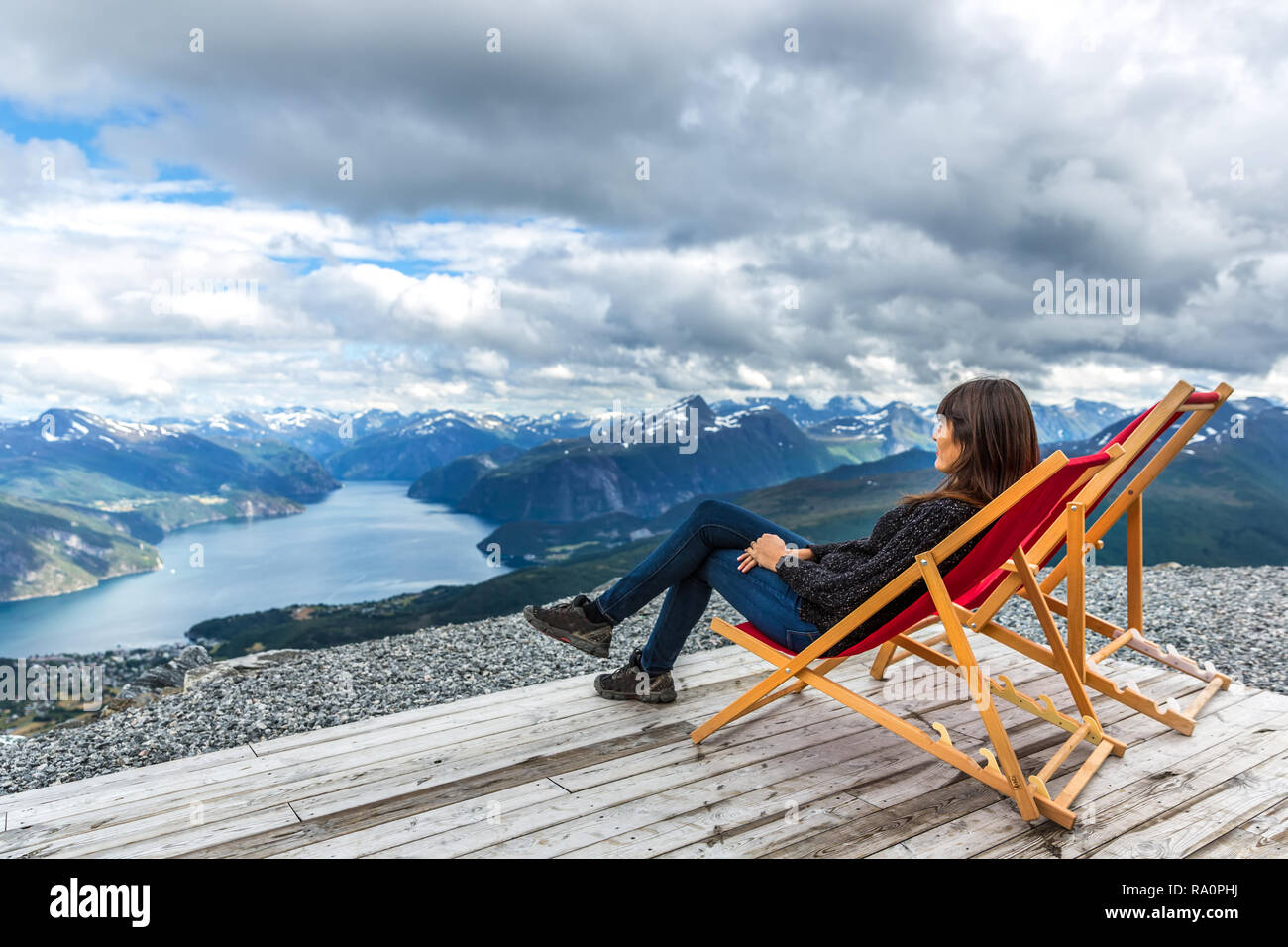 Jeune femme assise sur une chaise dans le haut des fjords avec une vue étonnante en Norvège Banque D'Images