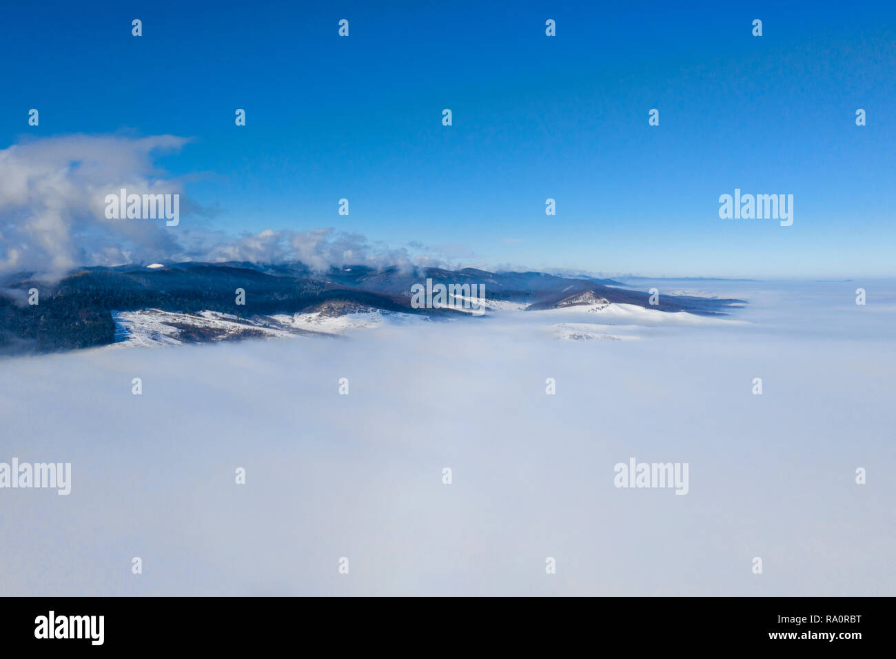 Drone volant au-dessus de la vallée brumeuse, hiver hill et la forêt derrière. Banque D'Images