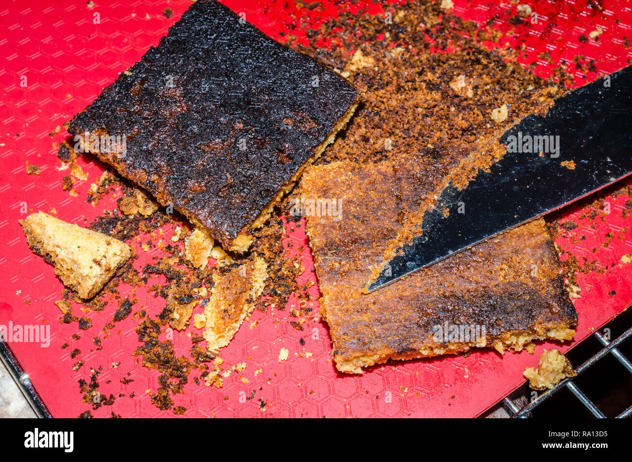 Barres-biscuits brûlés. Trop cuit noir Sweet Treat. En grattant la croûte exagéré d'un cookie bar, deuxième traiter a encore brûlé bas intacts. Banque D'Images