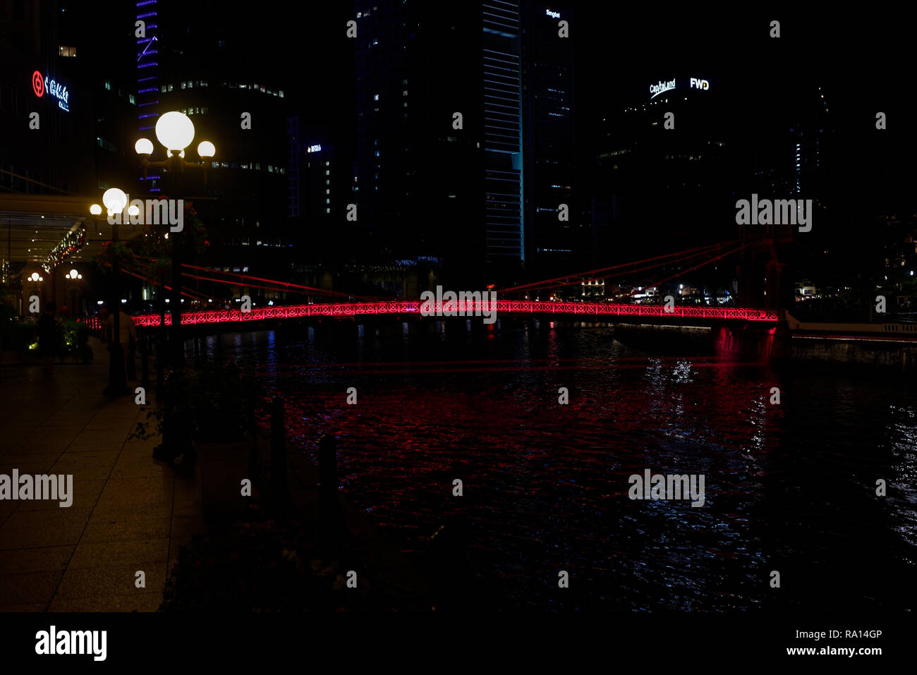 Le pont Cavenaugh, le seul pont suspendu sur la rivière Singapour, illuminée en rouge la nuit. Banque D'Images