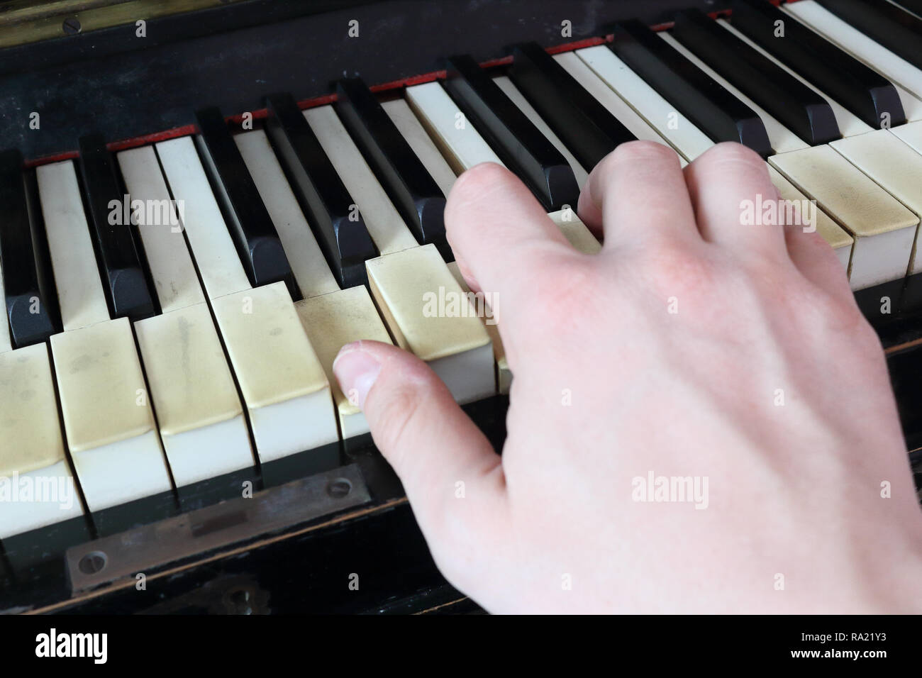 Une main droite jouer a G (SOL) d'accord sur un vieux piano noir avec  touches fissurés jaunies, appuyer sur G (SOL), B (SI), D (ré) Notes Photo  Stock - Alamy