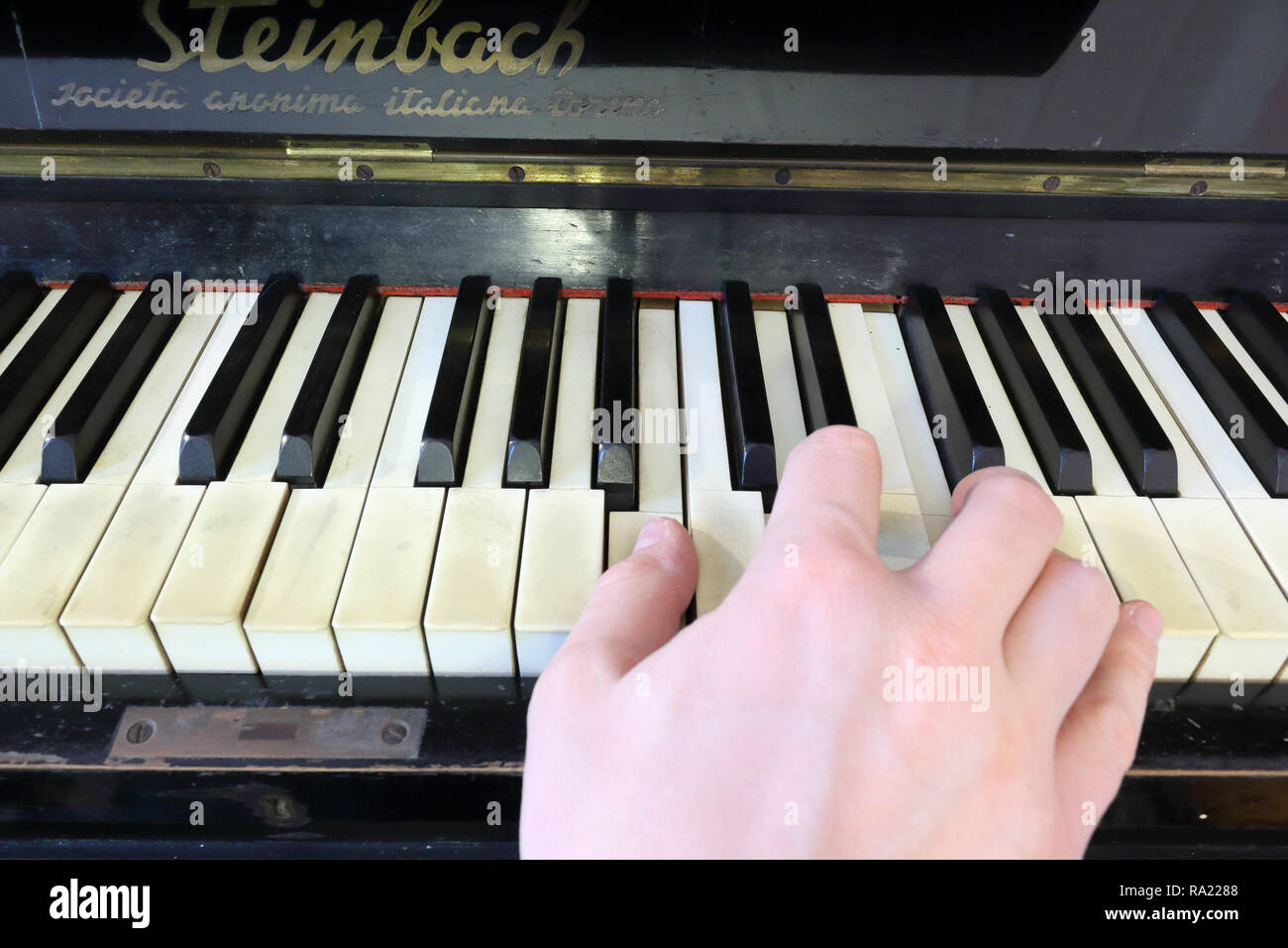 Une main droite jouer a B (SI) accord mineur sur un vieux piano noir avec touches fissurés jaunies, appuyant sur le B (SI), D (ré), F#  diesis (FA# ) Notes Banque D'Images