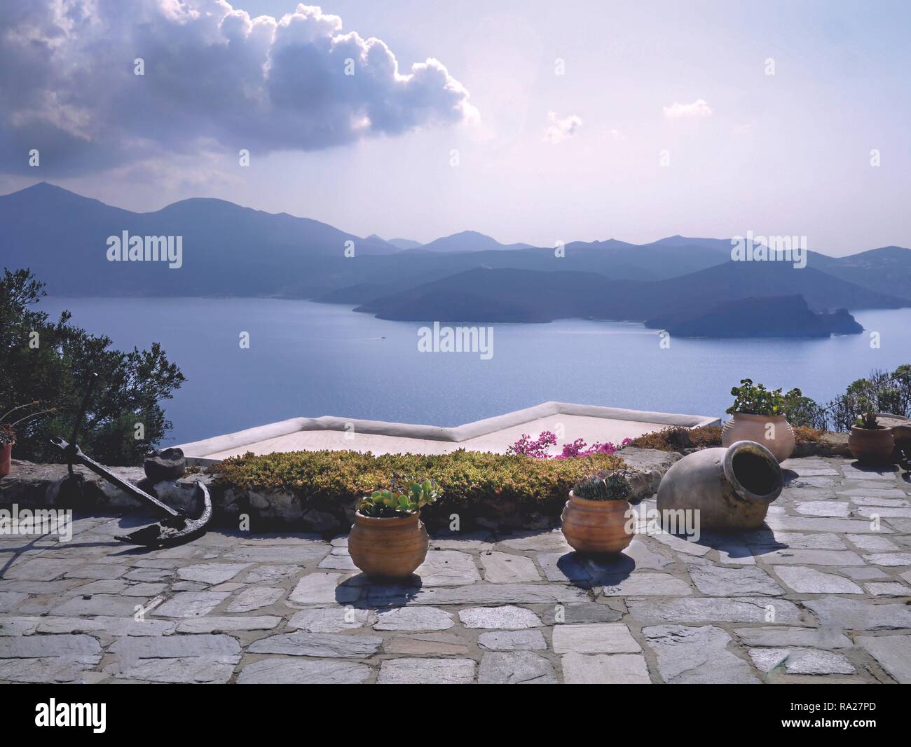 Vue panoramique sur mer et montagnes à partir d'un patio avec des jardinières en pierre et de fleurs, l'île de Milos, Grèce Banque D'Images