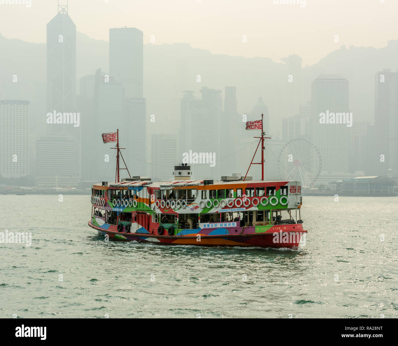 La "Nuit des étoiles colorées Star ferry naviguant dans ses échanges commerciaux du centre de Tsim Sha Tsui à Kowloon, avec les tours de l'île de Hong Kong en toile de fond. Banque D'Images