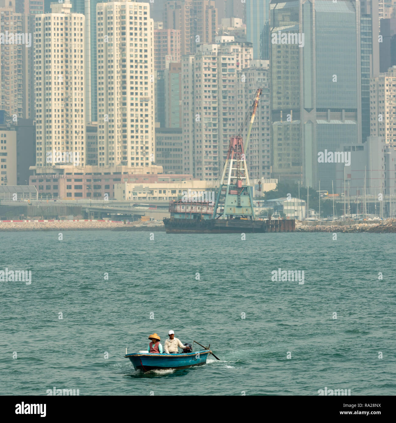 Un couple dans un petit bateau dans le port de Victoria, Hong Kong avec le tour de blocs de North Point à l'arrière-plan Banque D'Images