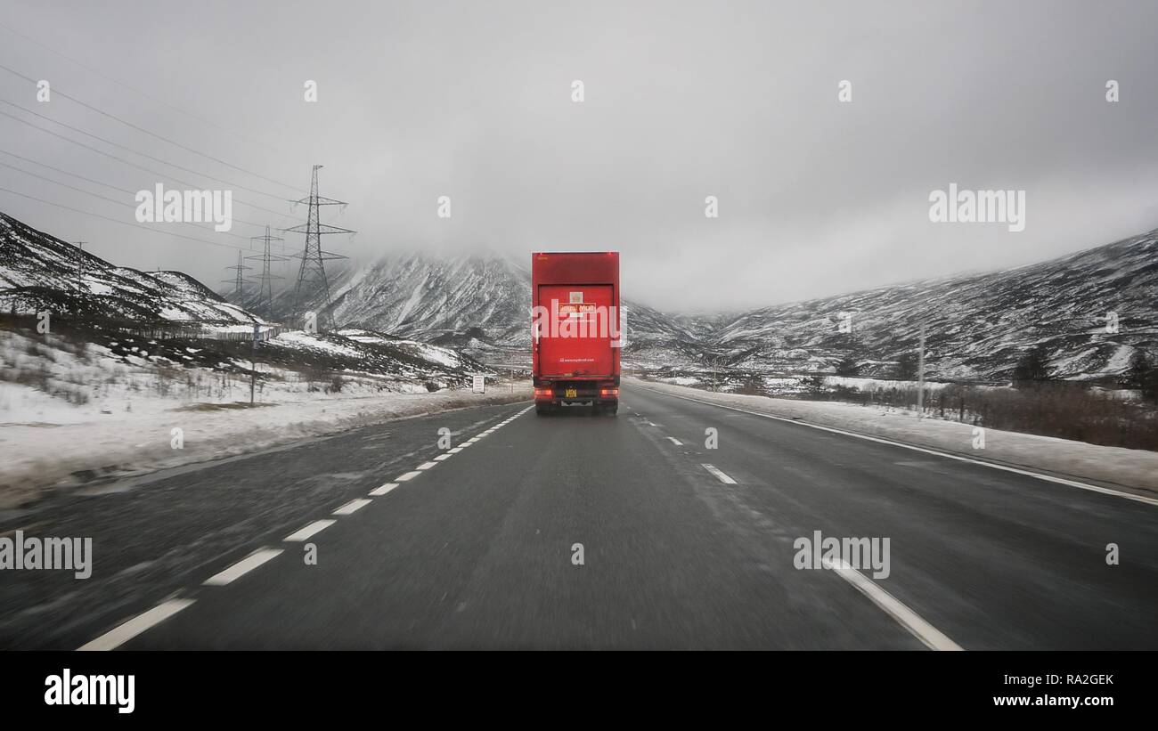 Un camion de livraison de courrier Royal solitaire de la conduite dans les highlands écossais en hiver, avant Noël, sur l'autoroute A9. Banque D'Images