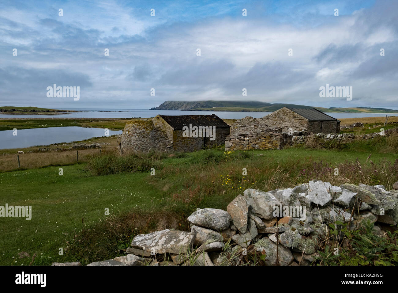 Un vieux croft house avec des murs en pierre donnant sur l'océan Atlantique dans les îles Shetland de l'Écosse sur un jour nuageux Banque D'Images
