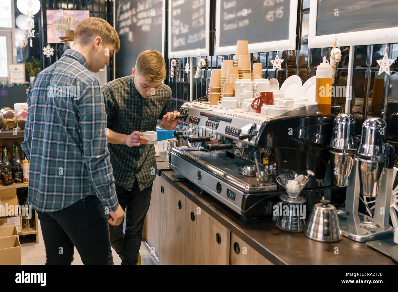 Coffee House, petite entreprise, homme barista près de la machine à café. Enseignement coaching barista expérimenté jeune homme pour préparer du café dans des cof Banque D'Images