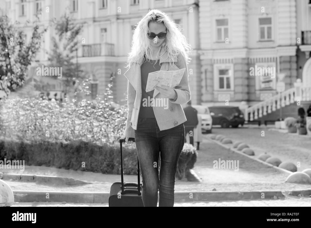 Young smiling blonde femme avec un sac de voyage et le téléphone marche à la ville rue, femme avec des lunettes avec de longs cheveux bouclés, noir et blanc photograp Banque D'Images