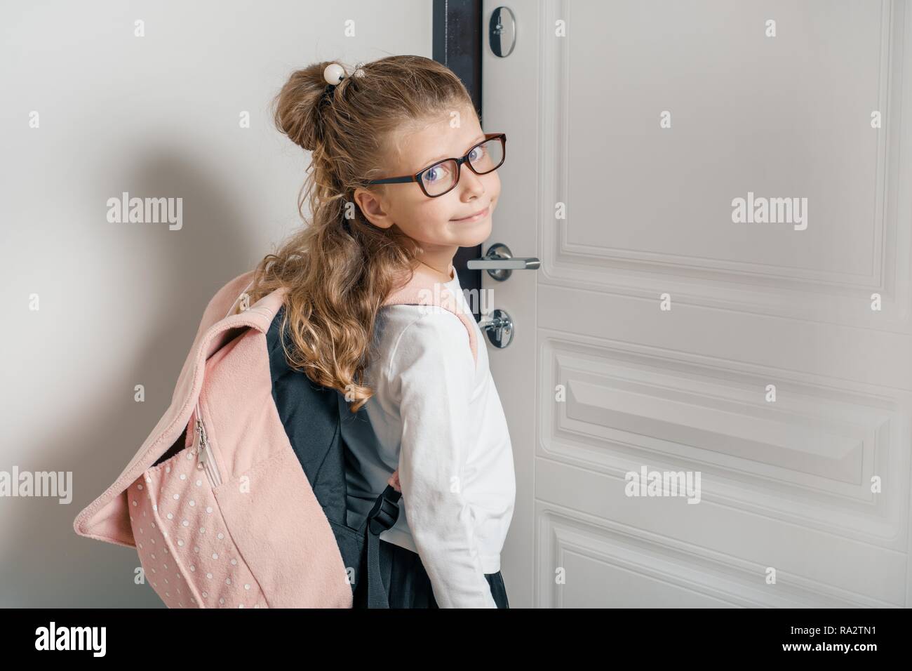 Peu jolie fille 6, 7 ans avec sac à dos pour l'école. Jeune fille  souriante, debout près de la porte de la chambre, enfant va à l'école Photo  Stock - Alamy