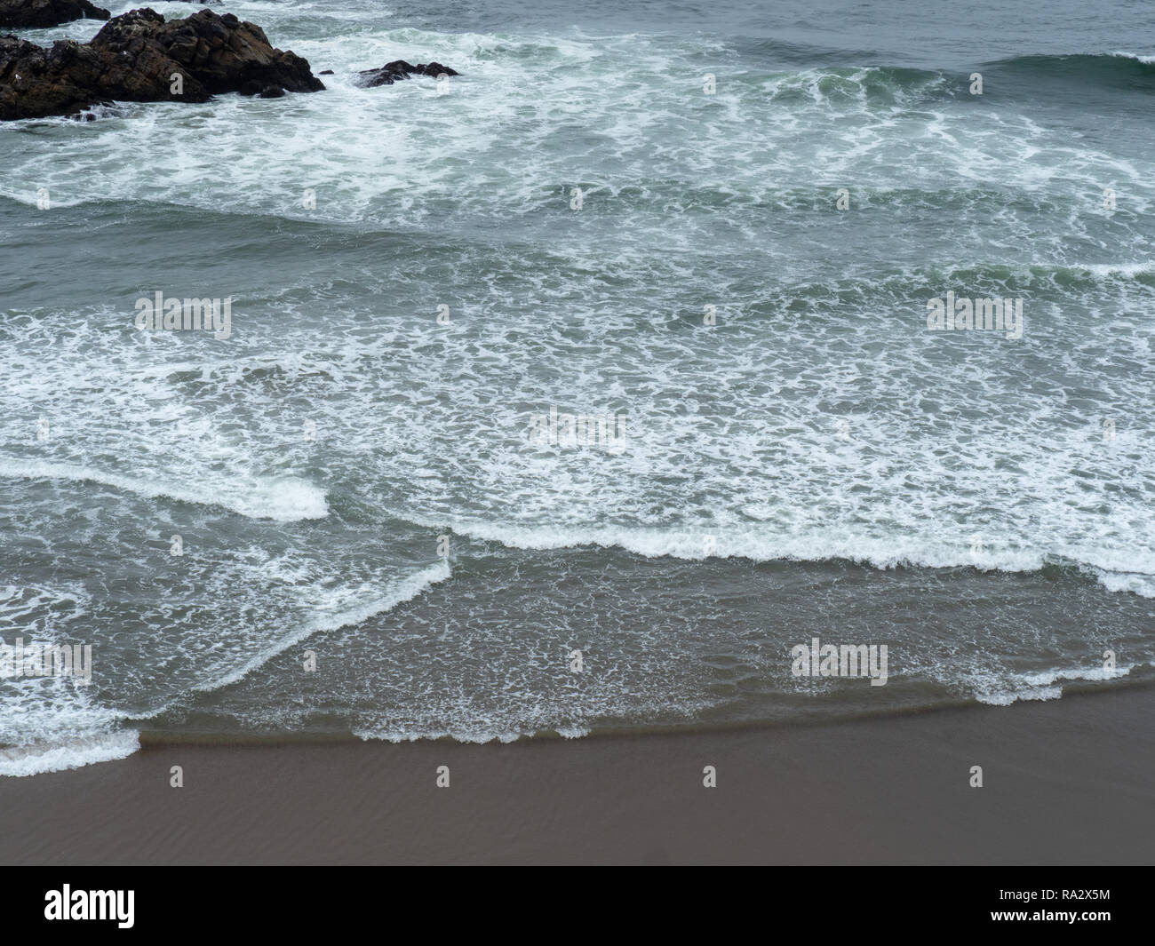Les vagues de l'océan Pacifique roulant sur une plage rapide sur une journée grise Banque D'Images