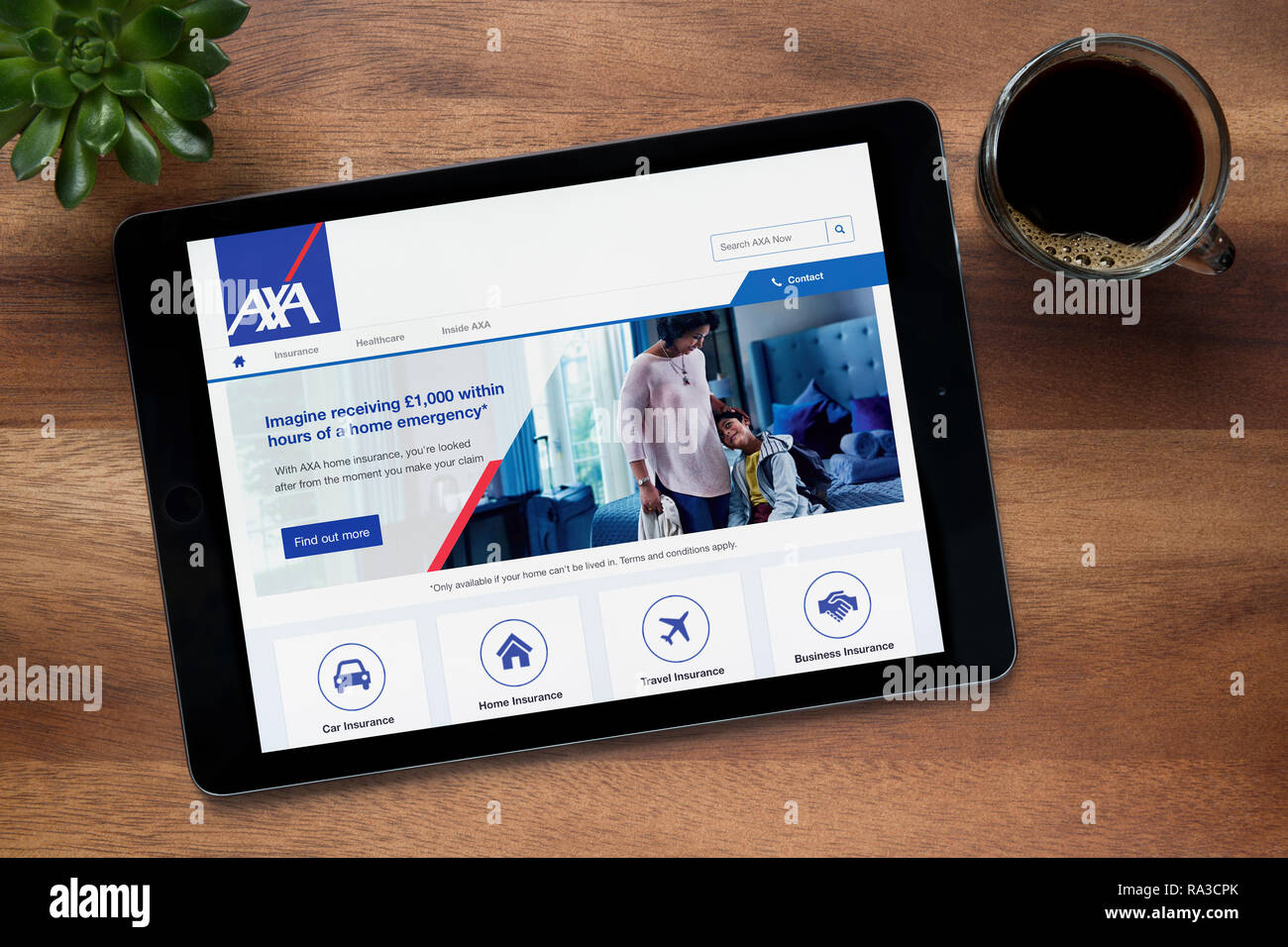 Le site web de l'assurance AXA est vu sur un iPad tablet, sur une table en bois avec une machine à expresso et d'une plante (usage éditorial uniquement). Banque D'Images