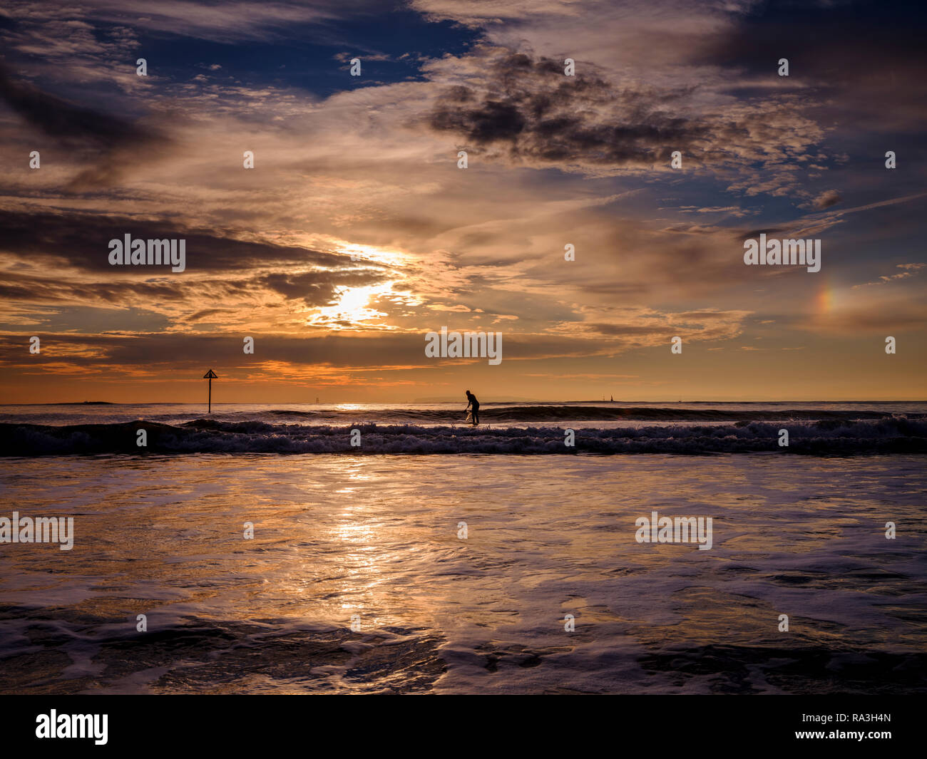 Une pagaie boarder West Wittering plage au coucher du soleil près de Chichester, West Sussex. Banque D'Images
