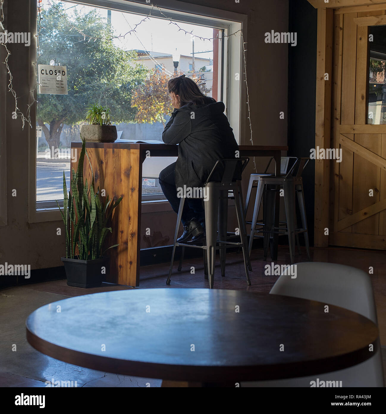 Femme dans un café à la recherche au travers d'une fenêtre Banque D'Images