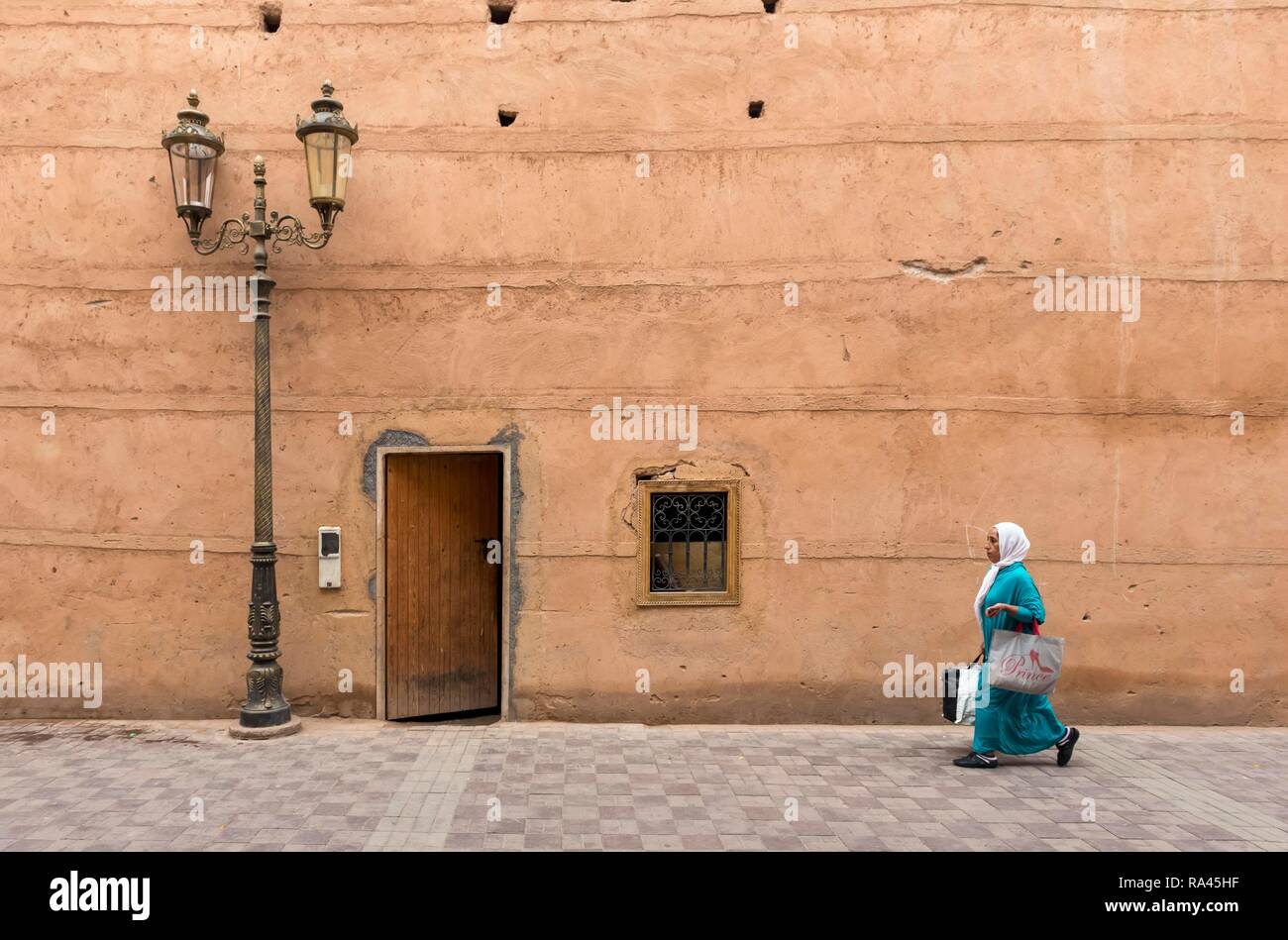Femme promenades le long des murs d'argile de Palais Badi à Marrakech, Maroc Banque D'Images