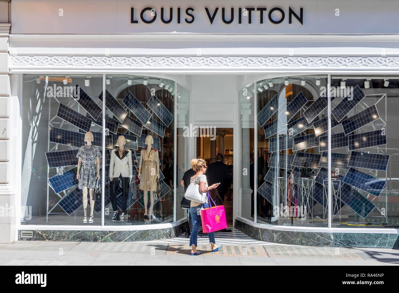 Les passants devant la vitrine du magasin de mode Louis Vuitton, Londres, Royaume-Uni Banque D'Images