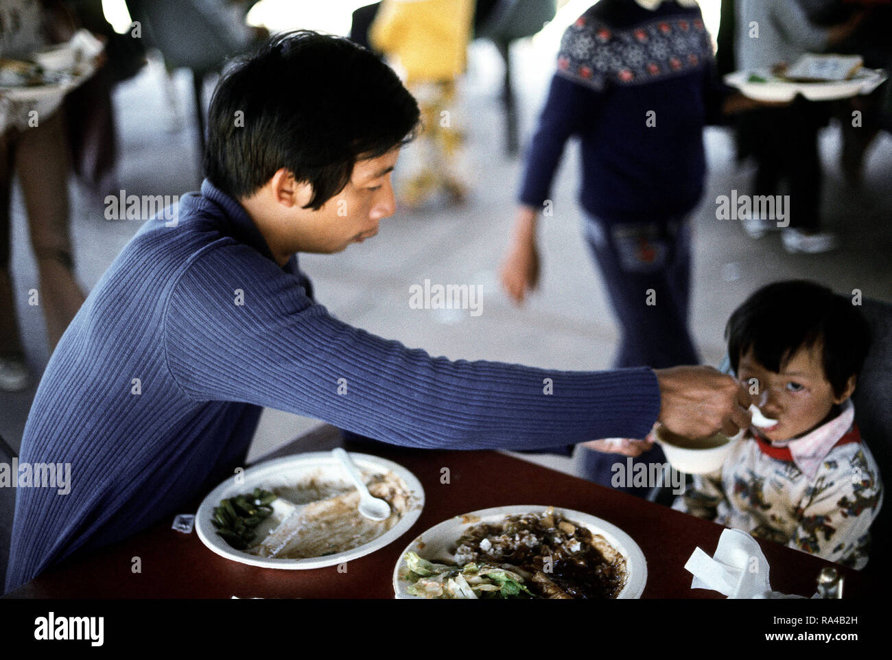 1975 - Un père nourrit ses enfants à un établissement de logements temporaires pour les réfugiés vietnamiens à Camp Pendleton, CA Banque D'Images