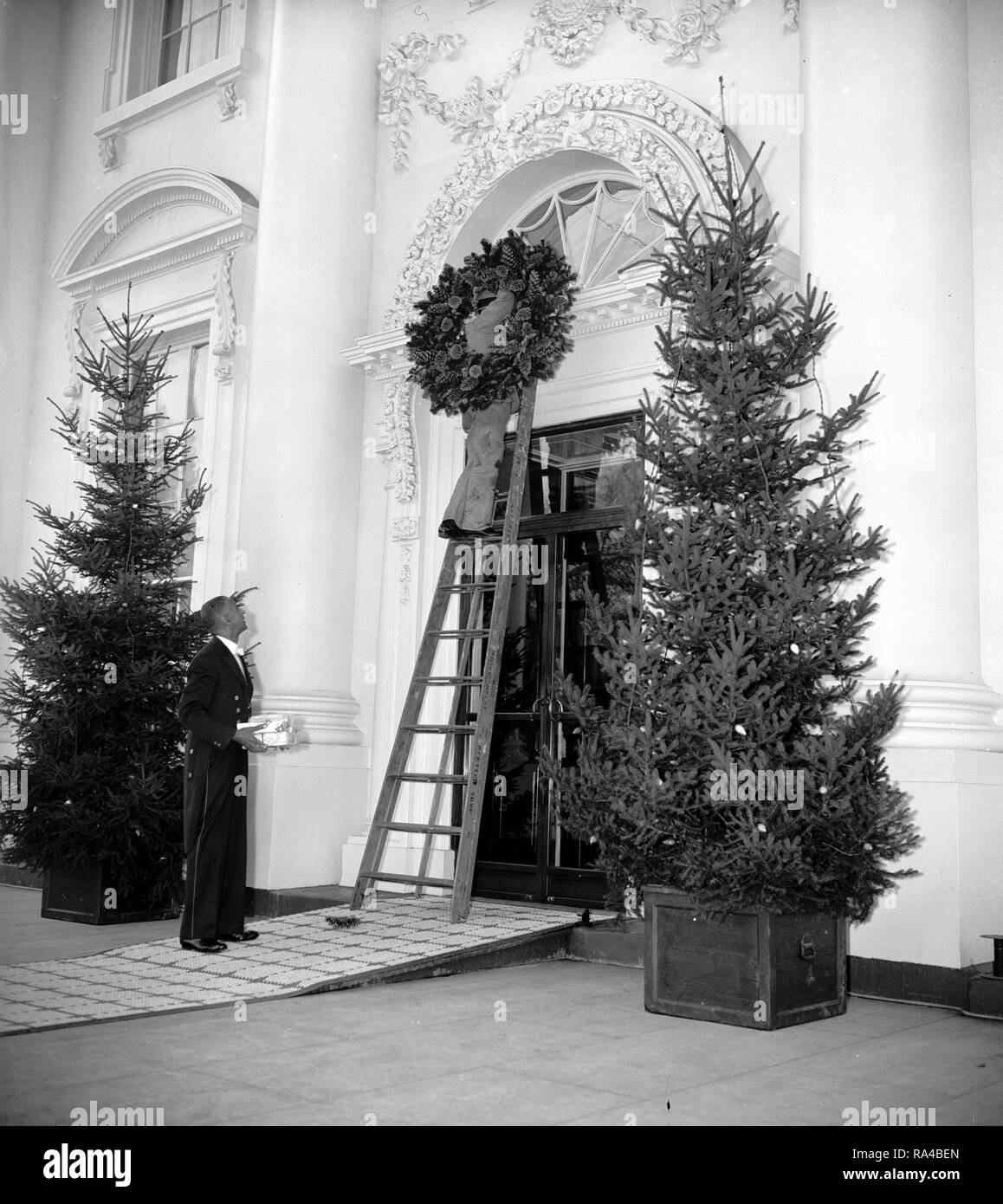 Esprit de Noël à l'air à la Maison Blanche. Washington D.C., 21 décembre. Ouvriers plaçant une couronne de Noël sur la porte à la Maison Blanche aujourd'hui. 12/21/1937 Banque D'Images