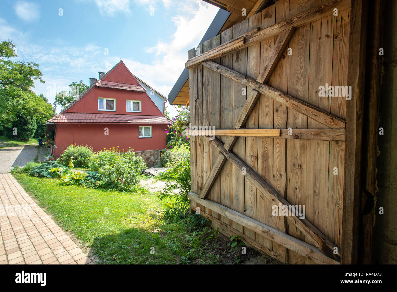 Porte en bois et un petit chemin qui mène à une ferme en gîte rouge avec jardins. Glich-w, Lesser Poland Voivodeship, Pologne Banque D'Images