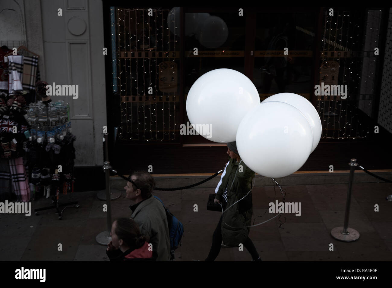 Femme avec trois gros ballons blancs sur Coventry Street, Londres, Angleterre. Banque D'Images