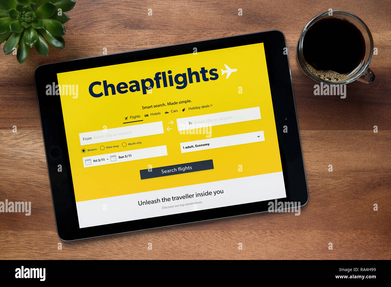 Le site internet de Cheapflights est vu sur un iPad tablet, sur une table en bois avec une machine à expresso et d'une plante (usage éditorial uniquement). Banque D'Images