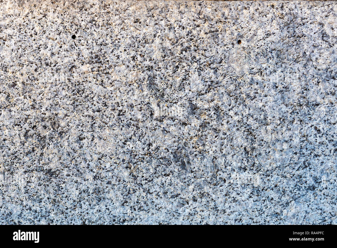 Un gros plan d'une surface de roche de granit gris traités plaque. Un fragment d'un mur de pierre de décoration. La texture du matériau granit gris lumineux. Banque D'Images