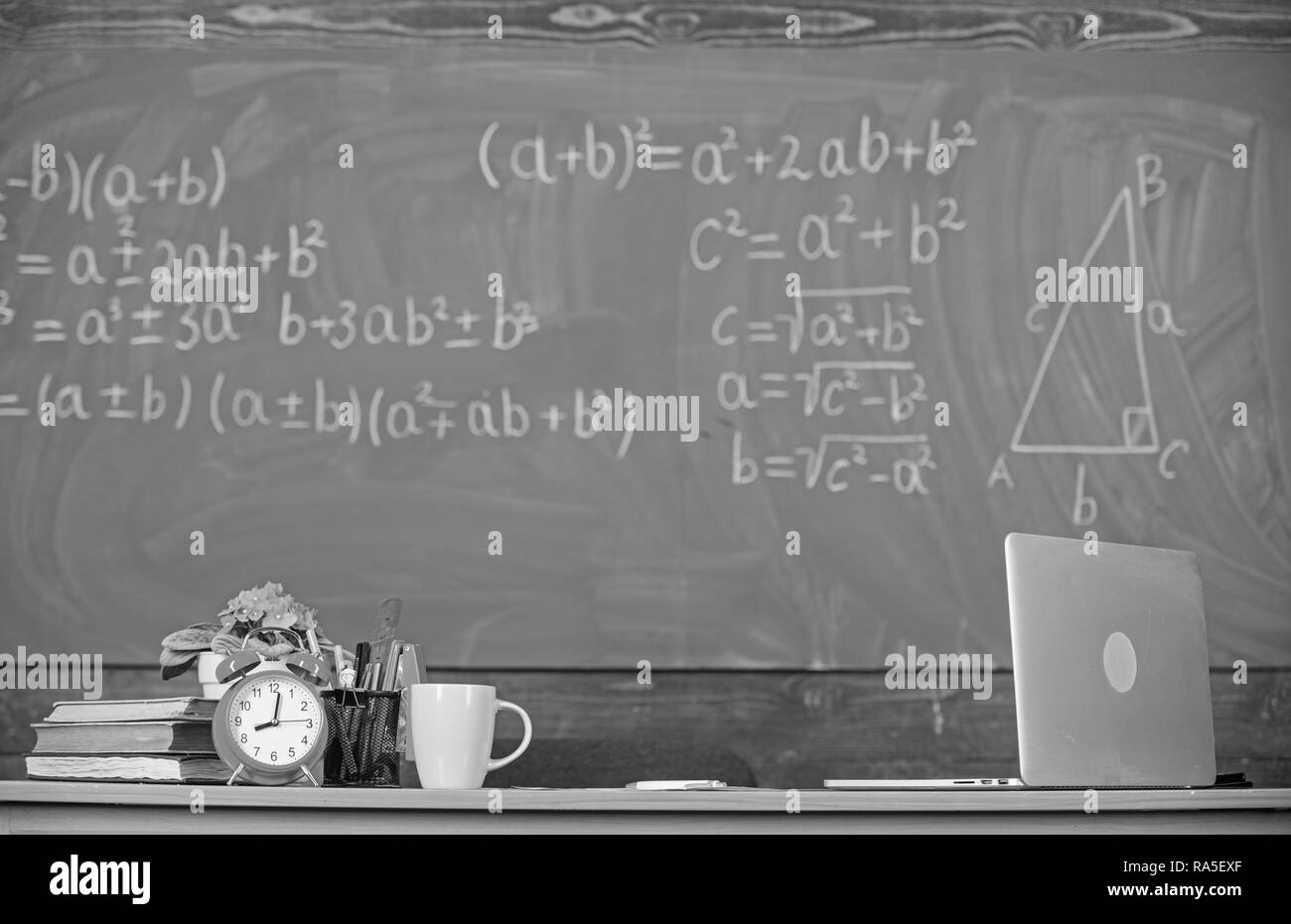 Les enseignants des attributs. Table avec des fournitures scolaires réveil livres et mug tableau classe arrière-plan. Conditions de travail que les futurs enseignants doivent tenir compte. Les enseignants traditionnels de travail. Banque D'Images
