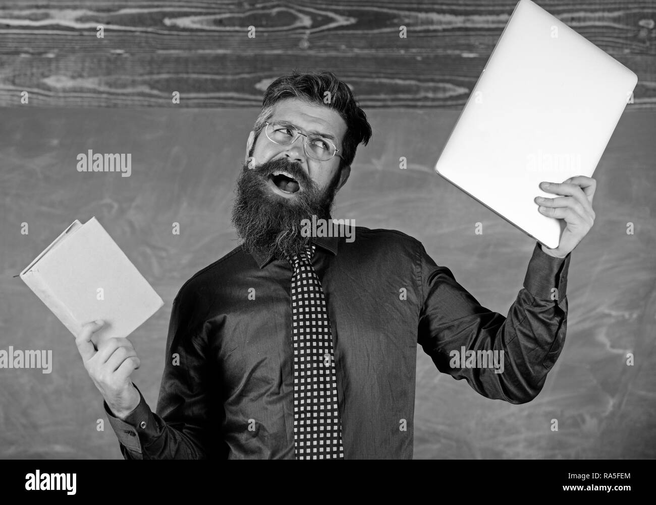 Qu'est-ce que vous le souhaitez. Hipster barbu de l'enseignant est titulaire d'adresses et ordinateur portable. Le choix d'enseignants de l'enseignement moderne approche. Papier contre numérique. Choisissez la méthode d'enseignement droit. Livre papier contre l'ordinateur portable. Banque D'Images