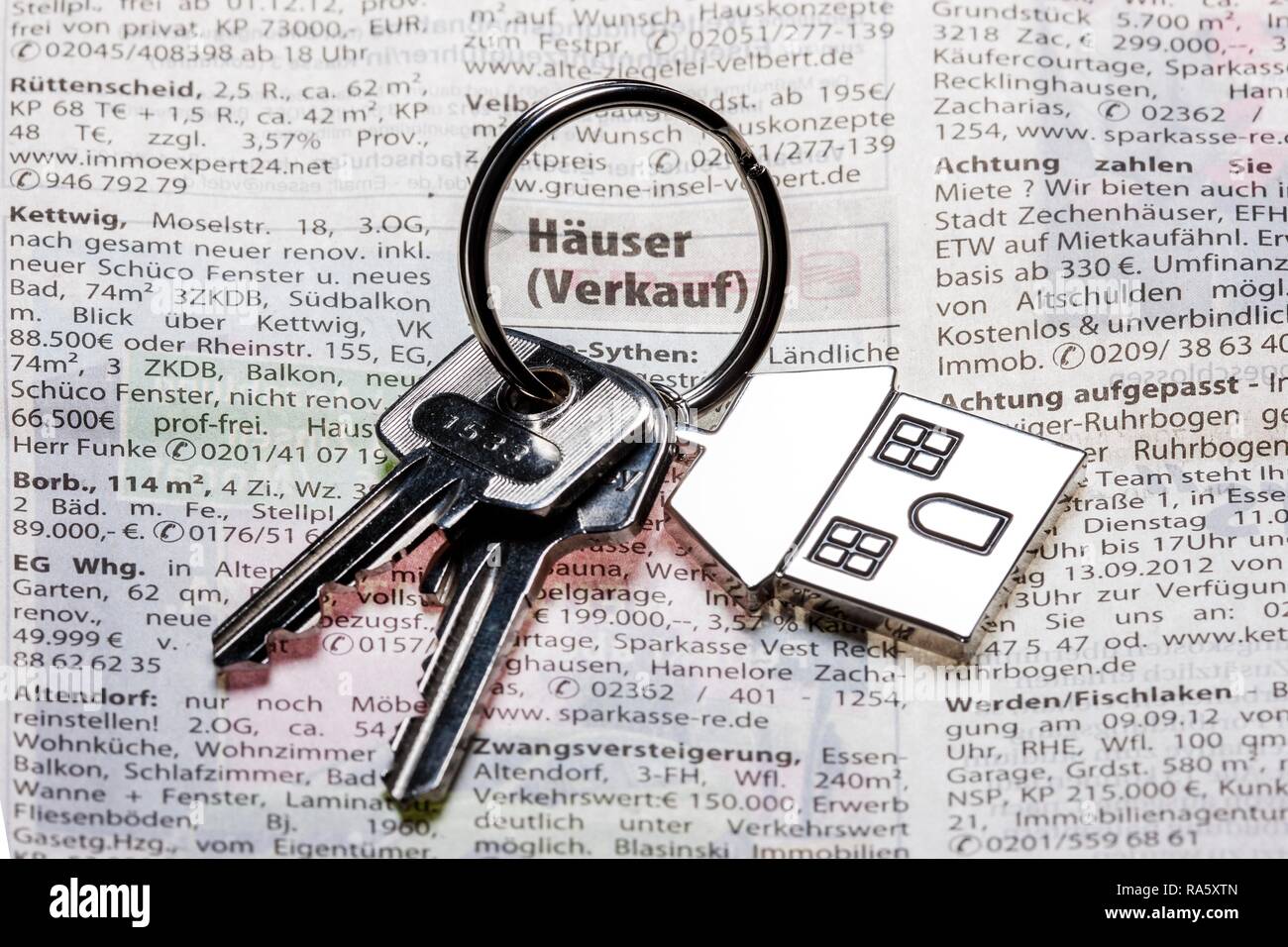 Deux clés avec une clé en métal en forme de tag comme une maison se trouvant sur la page de l'immobilier d'un quotidien allemand Banque D'Images