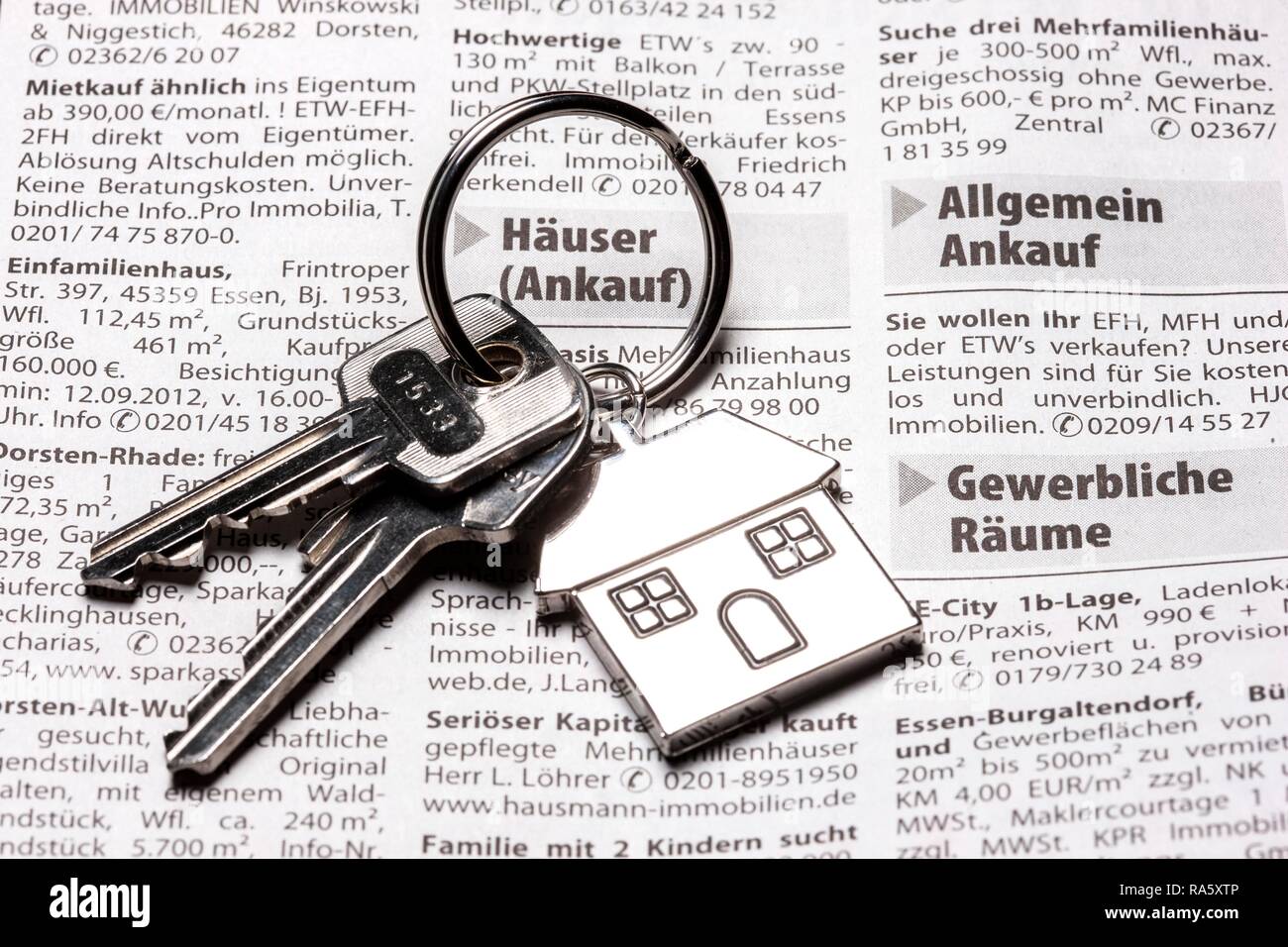Deux clés avec une clé en métal en forme de tag comme une maison se trouvant sur la page de l'immobilier d'un quotidien allemand Banque D'Images