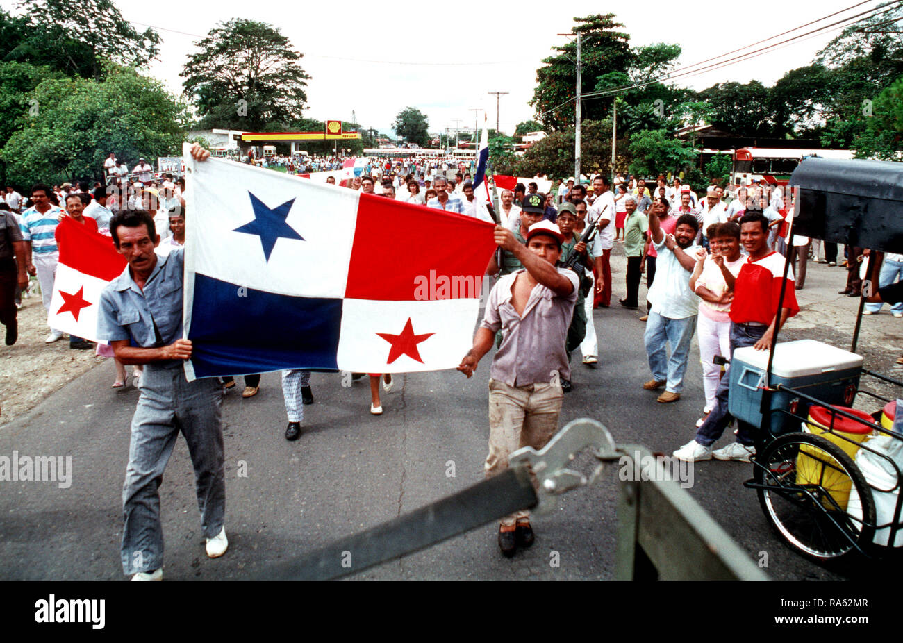 Les partisans de drapeaux de GEN Manuel Noriega face à une patrouille maritime de la Compagnie B, 2e Bataillon d'infanterie blindée. La foule dans les rues et ont formé un barrage routier avec deux bus, qui peut être vu dans l'arrière-plan. À proximité de la Force de défense panaméenne (PDF) soldats, dont deux sont debout à droite de l'indicateur dans l'avant-plan, ont refusé de se disperser la foule et les Marines ont pris une autre route pour compléter leur patrouille. Banque D'Images
