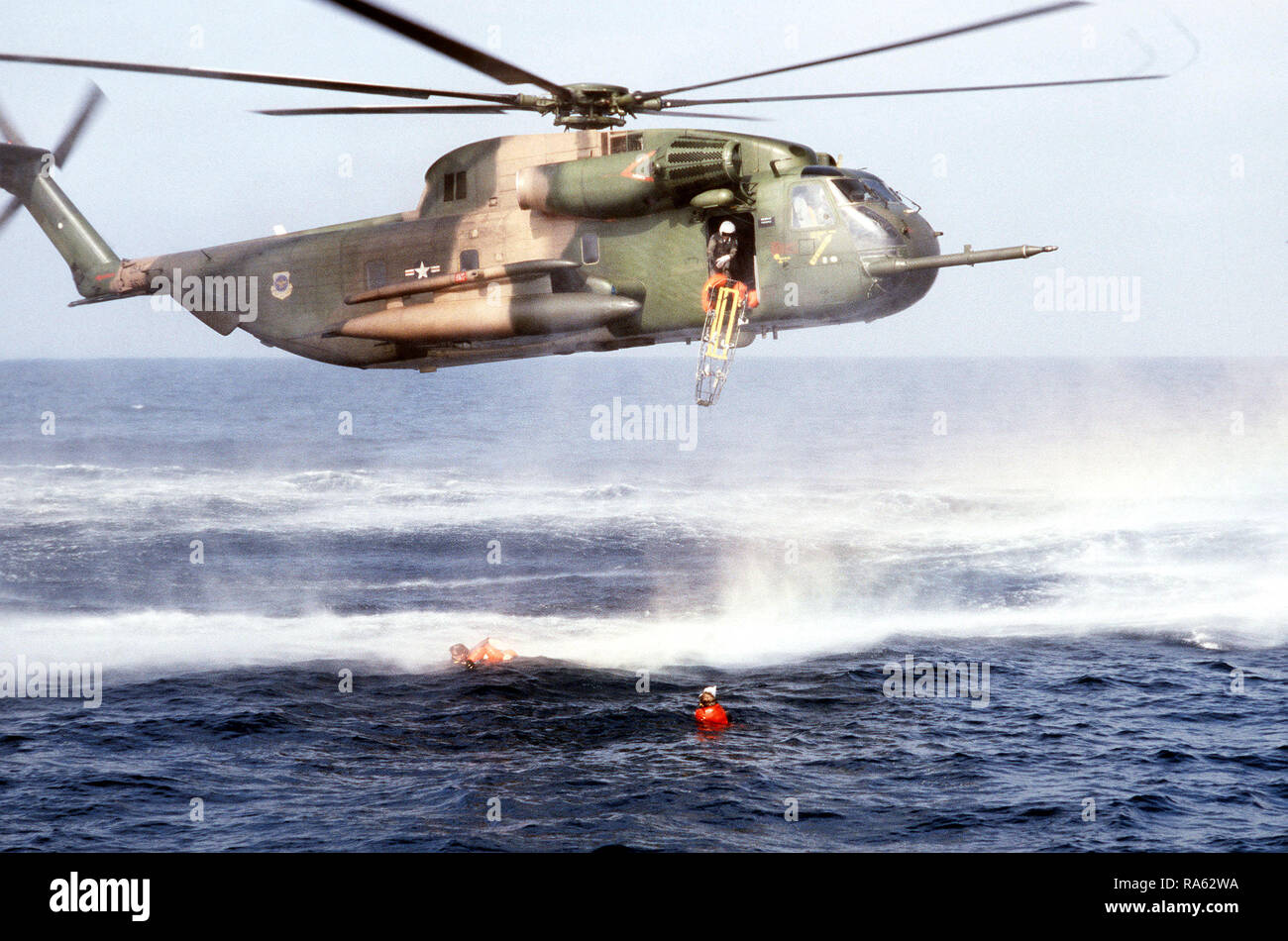 1978 - une litière est largué d'un hélicoptère en vol stationnaire HH-53 à pararescuemen du 55e Escadron de sauvetage et de récupération de l'aérospatiale, Eglin AFB, en Floride, comme ils aident un "survivant" flottant dans l'eau. L'exercice de sauvetage en mer est organisé pour un film production. Banque D'Images