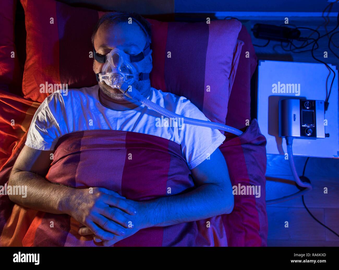 L'homme avec l'apnée du sommeil, porte un masque CPAP pendant le sommeil, masque respiratoire, qui pousse l'air dans les voies respiratoires en raison Banque D'Images