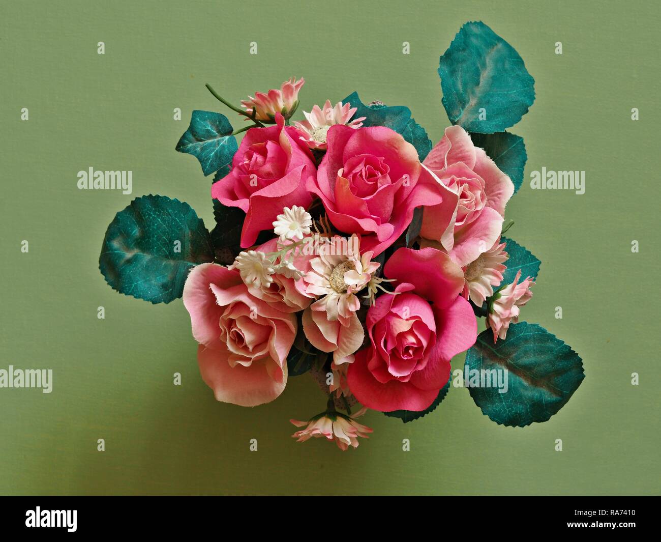 Bouquet de fleurs artificielles et de feuilles vertes vu de dessus avec un fond vert Banque D'Images