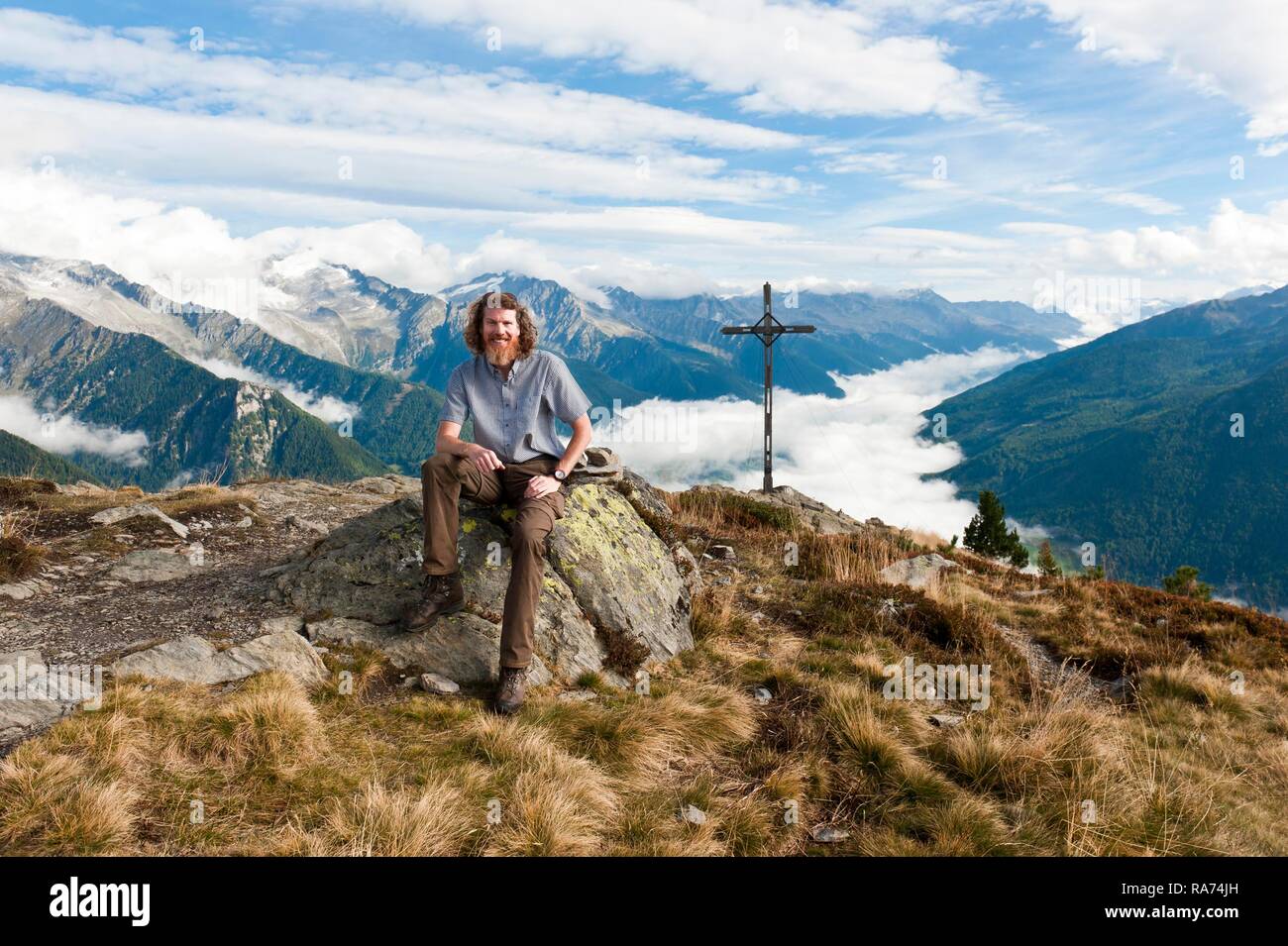 Randonneur randonneur, est assis sur des rochers, Kleiner Nock (2227 m) avec croix, dans la vue de Speikboden, Ahrntal, à Sand in Taufers, Campo Tures Banque D'Images