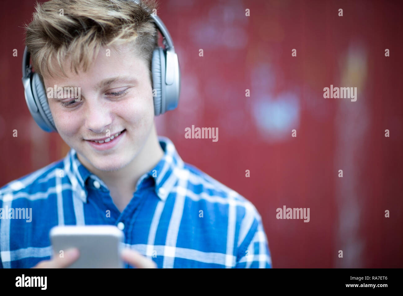 Teenage Boy portant un casque sans fil et d'écouter de la musique en milieu urbain Banque D'Images